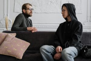 A psychologist and teenager engage in a counseling session in a cozy office setting.